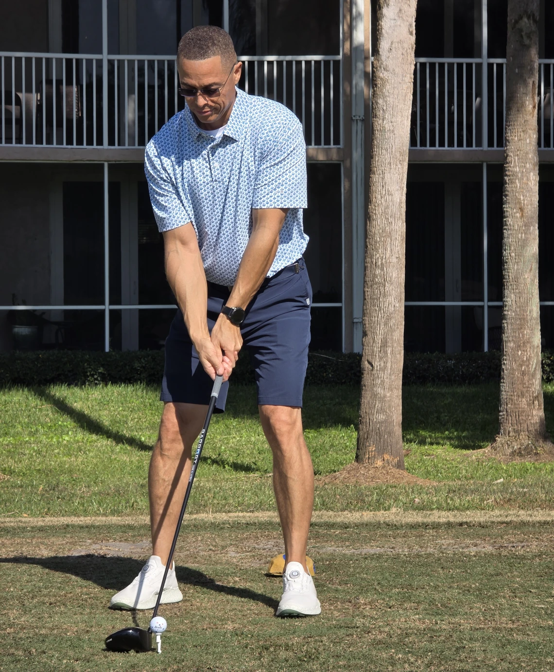 Man preparing to putt on a golf course in casual attire.